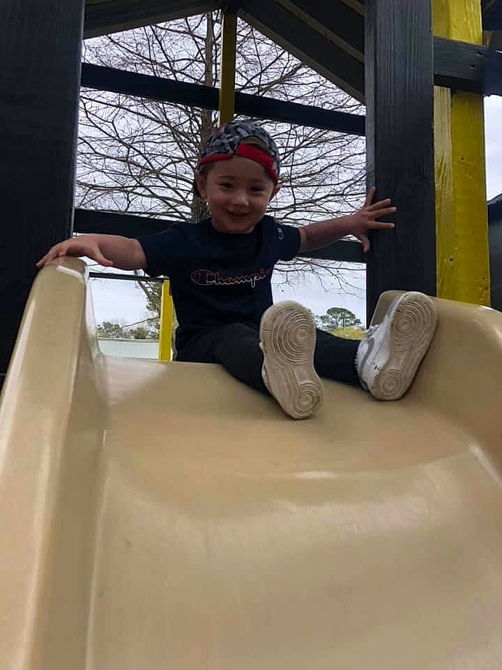 Zaydon is registered to the contest to win money with this photo: chute, city, fun, happy, hat, headwear, helmet, joy, leisure, outdoor_play_equipment, person, playground, playground_slide, recreation, shorts, sitting, smile, sneakers, t_shirt, toddler