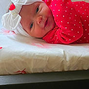 Daizlynn is registered to the contest to win money with this photo: baby, infant, headband, bow, red_clothing, polka_dots, smile, face, lying_down, floral_pattern, bed, blanket, cute, indoors, person, child, adorable, soft_light, portrait, young