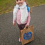 backpack, building, casual, child, clothing, daytime, footwear, girl, grass, nature, outdoor, paper_bag, pavement, person, pink_sweater, portrait, sidewalk, smile, trees, white_scarf