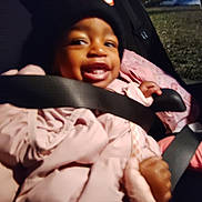 Kenyatta joined the competition — help win amazing prizes! child, toddler, smiling, car_seat, seatbelt, pink_coat, black_hat, red_bow, outdoor, nighttime, happy, person, clothing, baby, cute, warm_clothes, face, hands, sitting, portrait