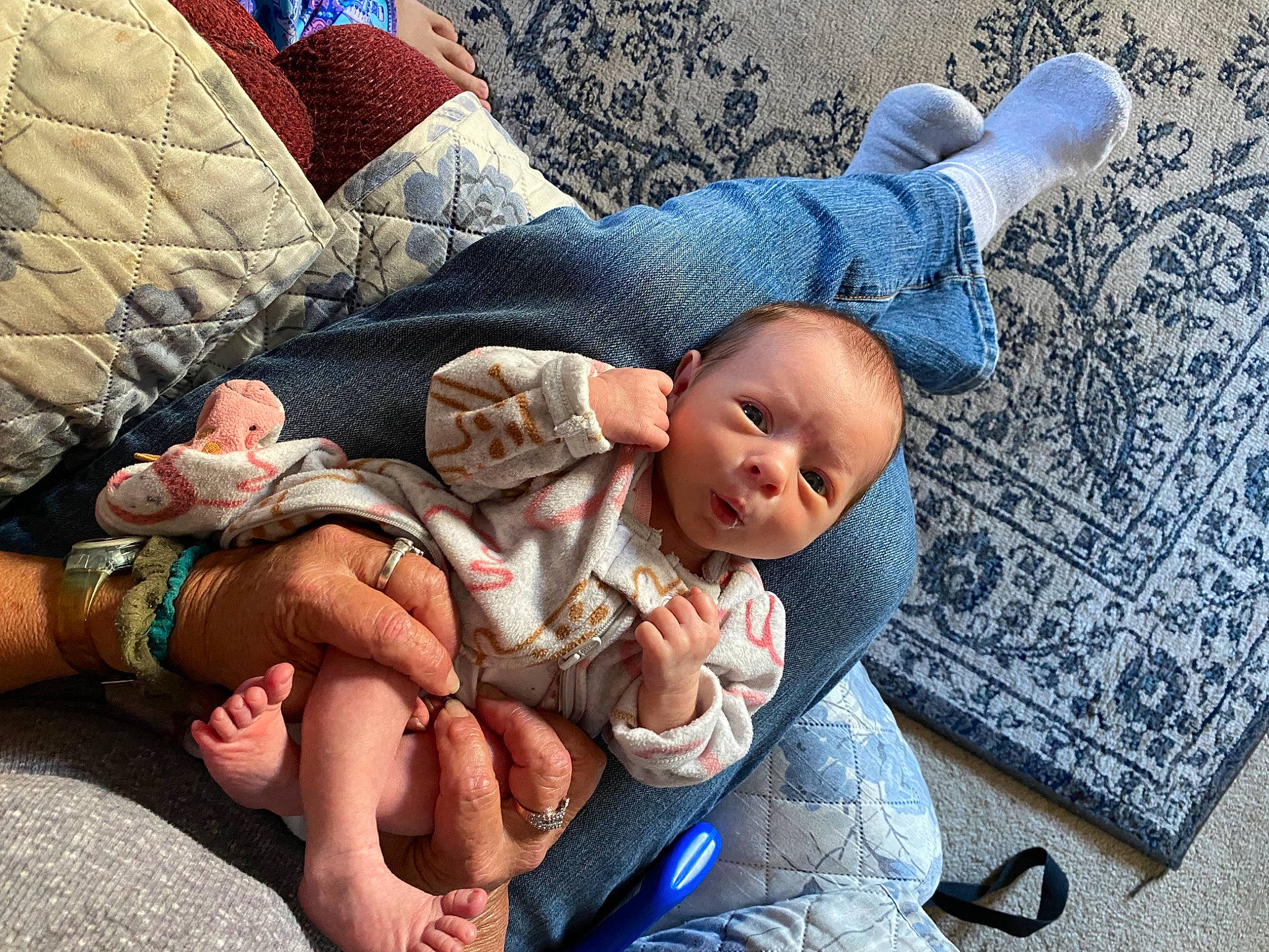 Eliana is registered to the contest to win money with this photo: baby, baby_toddler_clothing, blue, cheek, child, comfort, couch, finger, foot, hand, happy, human_body, human_leg, lap, mouth, person, sitting, skin, thigh, thumb