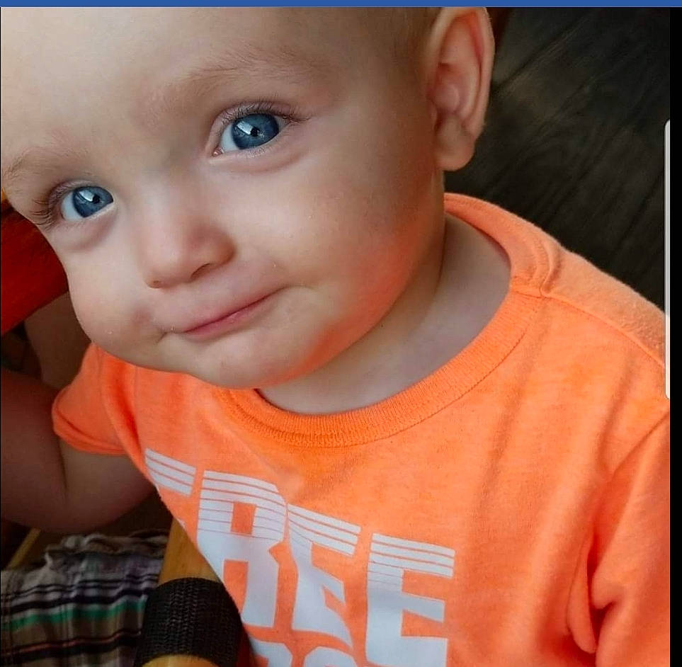 Bryer is registered to the contest to win money with this photo: boy, cheek, child, chin, ear, eye, eyebrow, face, finger, forehead, head, infant, lip, mouth, nose, orange, organ, person, skin, smile