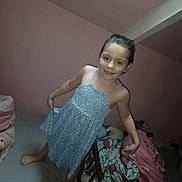 Louna participe au concours pour gagner de l'argent avec cette photo : barefoot, bed, bedding, bedroom, blanket, blue_dress, child, girl, hair_up, happy, indoor, mattress, pillow, pink_wall, portrait, posing, skylight, smiling, stuffed_toy, young_child