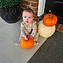 Mckenna is registered to the contest to win money with this photo: baby, pumpkin, fall, autumn, porch, brick_wall, plant, greenery, door, orange, white_pumpkin, child, cute, sitting, holding, outdoor, seasonal, holiday, decor, front_door