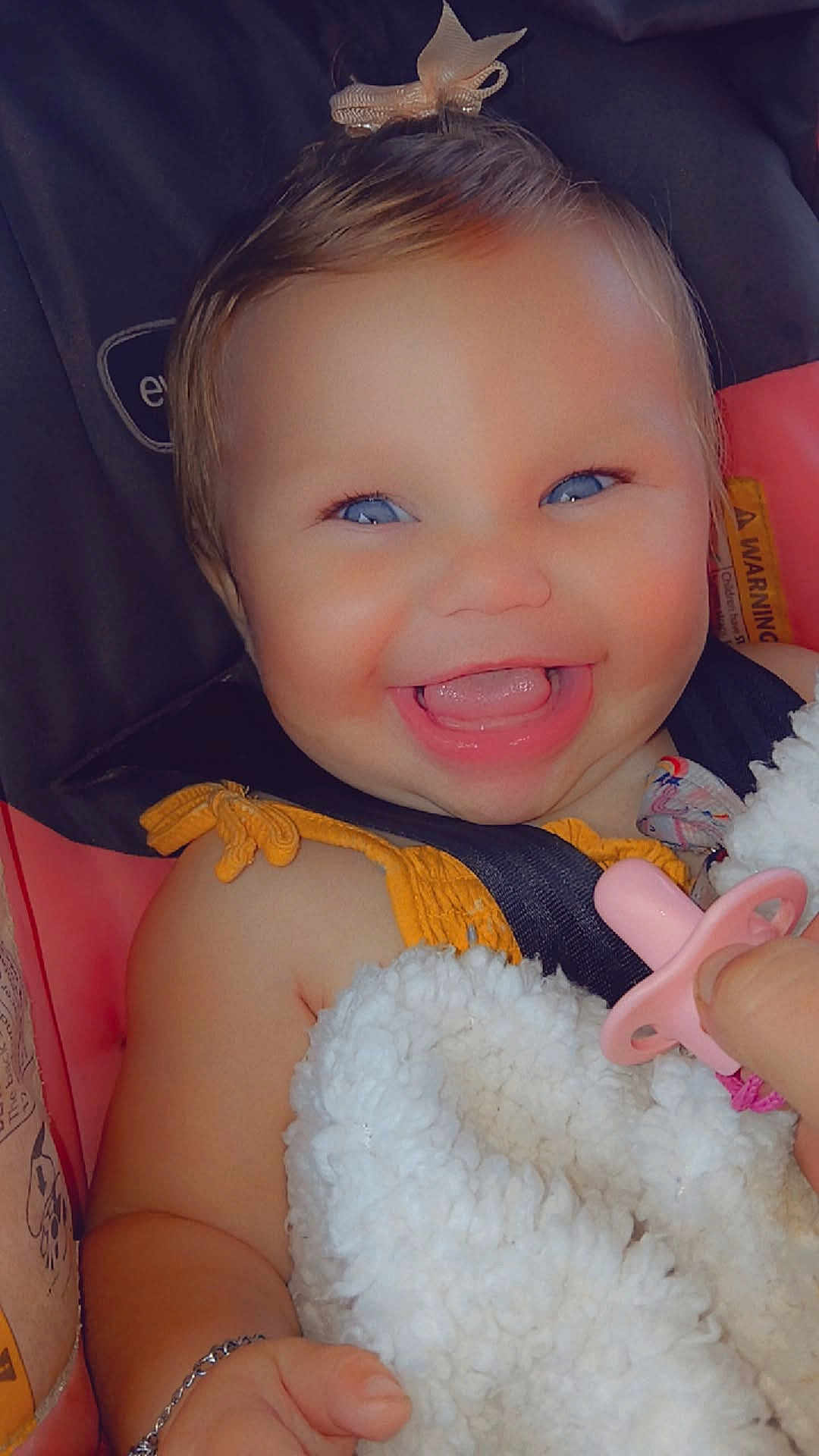 Hadley is registered to the contest to win money with this photo: baby, smiling, blue_eyes, blanket, pacifier, car_seat, bow, child, happy, cute, face, infant, clothing, hand, portrait, seatbelt, closeup, skin, baby_girl, expressive
