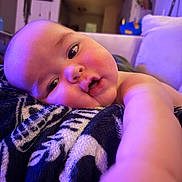 Milo joined the competition — help win amazing prizes! baby, infant, face, arm, blanket, indoor, home, soft_lighting, patterned_blanket, curious, closeup, person, child, relaxing, couch, furniture, expression, skin, head, portrait