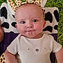 baby, infant, giraffe_headband, blanket, grass, cute, face, expression, child, clothing, portrait, lying_down, animal_print, headwear, toddler, outdoor, playful, closeup, smile, young