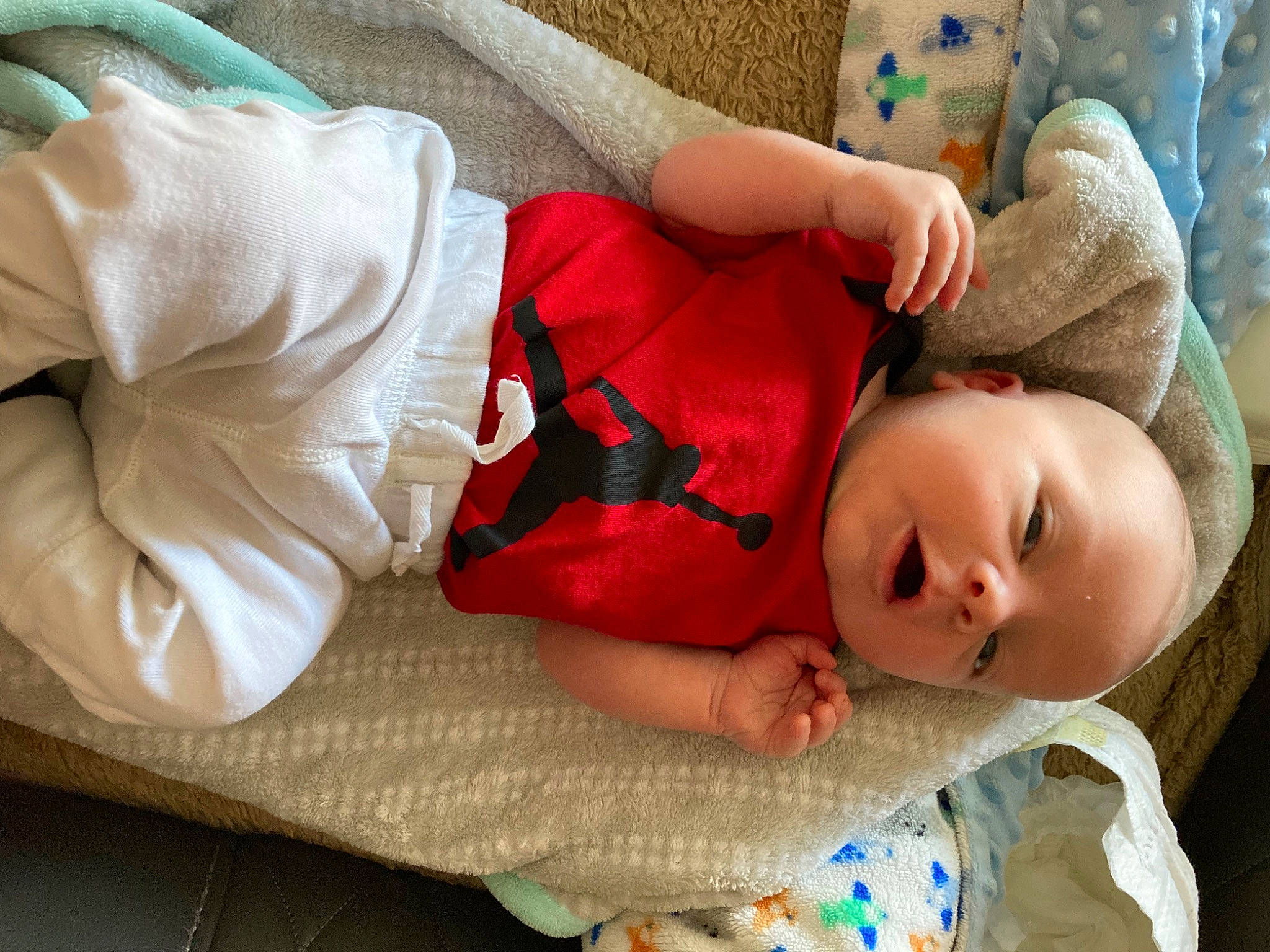 Weston is registered to the contest to win money with this photo: arm, baby_toddler_clothing, bedding, child, comfort, eye, hand, head, human_body, joint, linens, mammal, person, plant, sitting, skin, sleeve, textile, toy, tree