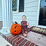 Antonio joined the competition — help win amazing prizes! baby, pumpkin, carved_pumpkin, bat_design, porch, brick_steps, doormat, door, window, column, cozy_clothing, smiling, sitting, outdoor, fall, holiday, decor, child, person, front_porch