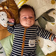 Nino a rejoint le concours — aidez-le/la à gagner de superbes lots ! baby, infant, striped_onesie, pillow, blanket, lion_pillow, crib, face, expression, cute, child, sleeping_area, soft_toys, patterned_clothing, indoor, young_child, lying_down, furniture, baby_bedding, portrait