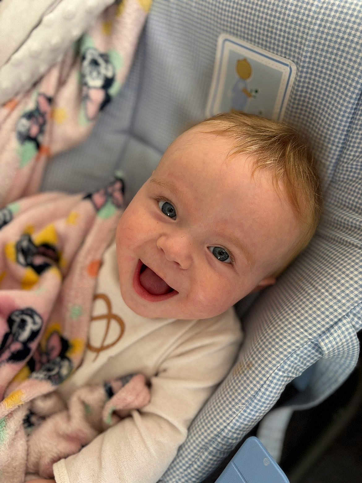 Maylan participe au concours pour gagner de l'argent avec cette photo : baby, baby_garment, blanket, blue_eyes, child, closeup, clothing, cozy, cute, face, greeting, happy, head, indoor, infant, patterned_blanket, portrait, seated, smiling, soft_texture