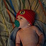 baby, infant, pacifier, red_hat, blanket, striped_blanket, towel, lying_down, indoors, cute, child, headwear, sleepwear, skin, newborn, resting, young_child, beanie, portrait, baby_boy
