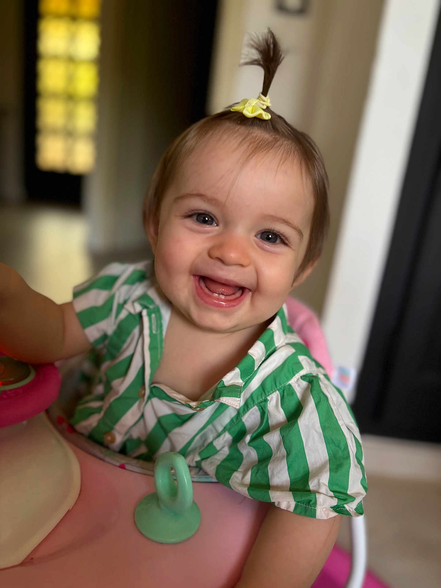 Lily-Rose participe au concours pour gagner de l'argent avec cette photo : baby, child, smiling, happy, face, portrait, indoors, green_striped_shirt, pink_baby_walker, baby_teeth, hair_ponytail, yellow_scrunchie, cute, infant, person, playful, closeup, young_child, cheerful, baby_toy