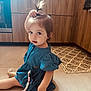toddler, child, blue_dress, ponytail, pacifier_clip, kitchen, floor, tile_floor, wooden_cabinets, patterned_rug, indoor, young_child, cute, sitting, playful, baby, person, hair, small_child, curious