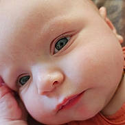 Aria is registered to the contest to win money with this photo: awake, baby, blue_eyes, cheeks, child, close_up, coral_clothing, curious, eyes, face, indoor, infant, mouth, nose, outfit, patterned_background, photography, portrait, smiling, soft_lighting