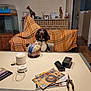 dog, soccer_ball, table, blanket, giraffe_figurine, figurine, plaid, indoor, room, chair, magazines, pliers, wall_art, doorway, decor, pet, animal, brown, white, collar