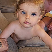 Maé a rejoint le concours — aidez-le/la à gagner de superbes lots ! toddler, child, blue_eyes, blonde_hair, couch, sofa, hand_holding, adult, indoor, curious, climbing, person, skin, face, living_room, tattoo, bare_chest, pillow, close_up, expression