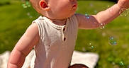 Ayan is registered to the contest to win money with this photo: baby, child, outdoor, bubbles, grass, sunlight, blue_sky, person, sleeveless_shirt, curious, playing, summer, nature, skin, arm, lap, daylight, greenery, happy, portrait