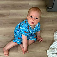 Ayan is registered to the contest to win money with this photo: toddler, child, baby, floor, wooden_floor, blue_clothing, fish_pattern, sitting, indoors, blanket, curious, cute, portrait, crawling, infant, person, skin, hand, foot, head
