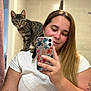 Athena participe au concours pour gagner de l'argent avec cette photo : woman, cat, mirror, selfie, bathroom, smartphone, tabby_cat, shoulder, tattoo, white_shirt, long_hair, smile, earrings, indoor, reflection, person, cute, pet, friendly, casual