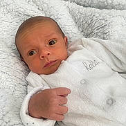 Kassym participe au concours pour gagner de l'argent avec cette photo : newborn, baby, infant, white_blanket, white_clothing, cozy, cute, portrait, face, hand, sleepwear, soft_texture, resting, indoors, young_child, curious, expression, closeup, skin, human