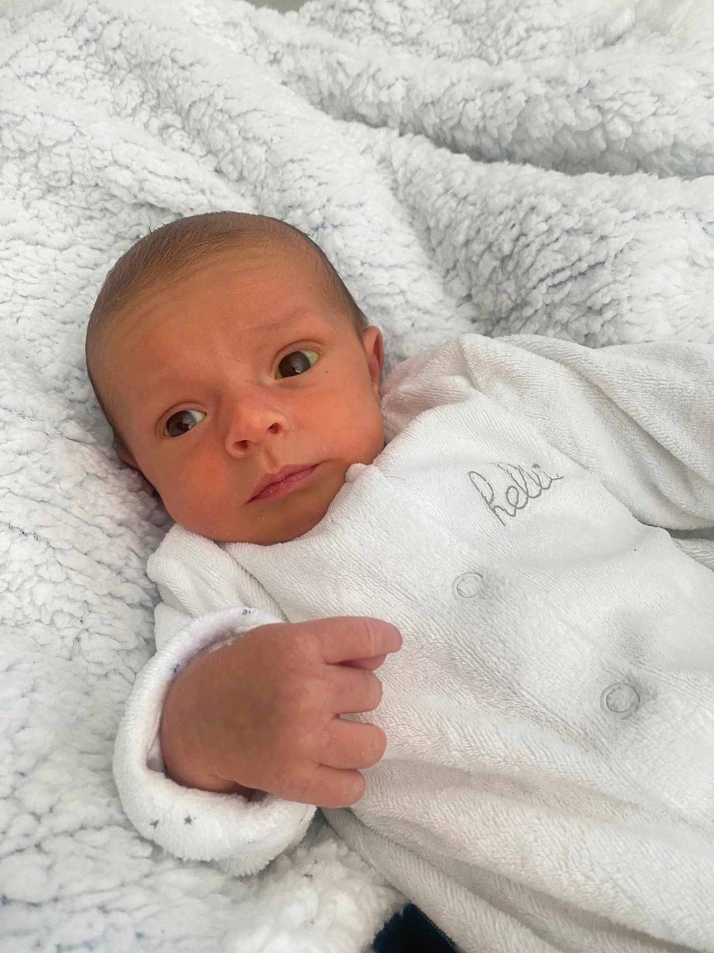 Kassym participe au concours pour gagner de l'argent avec cette photo : newborn, baby, infant, white_blanket, white_clothing, cozy, cute, portrait, face, hand, sleepwear, soft_texture, resting, indoors, young_child, curious, expression, closeup, skin, human