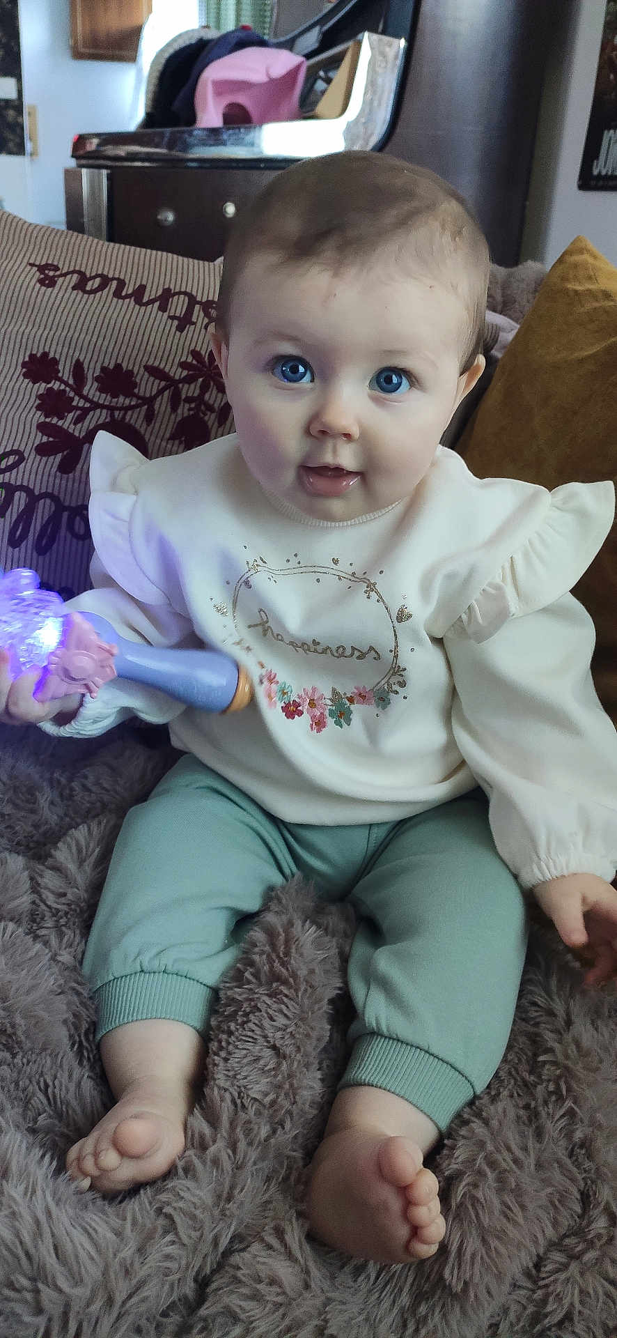 Louise participe au concours pour gagner de l'argent avec cette photo : baby, blanket, blue_eyes, child, clothing, cozy, curious, cute, expression, face, foot, glowing_toy, hand, home_interior, indoor, person, pillow, sitting, soft_texture, toy