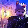 baby, blue_light, child, cozy, cute, festive, frosty_branches, glow, hat, holiday, indoors, jacket, lantern, light, orange_light, portrait, reindeer_hat, smiling, winter, winter_clothing