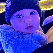 Louison participe au concours pour gagner de l'argent avec cette photo : baby, child, face, portrait, hat, beanie, jacket, fur, blue_light, winter_clothing, close_up, eyes, cute, warm_clothing, night, lights, outdoor, person, infant, expression