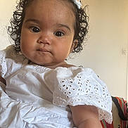 Taïly a rejoint le concours — aidez-le/la à gagner de superbes lots ! adorable, baby, background, bag, child, closeup, clothing, curly_hair, cute, expression, eyes, face, headband, indoor, portrait, sitting, skin, soft_light, white_dress, young