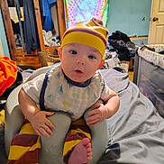 Jackson joined the competition — help win amazing prizes! baby, infant, child, indoor, seat, clothing, hat, pants, bib, foot, face, expression, furniture, bed, room, colorful, tie_dye, wooden_wardrobe, basket, blanket