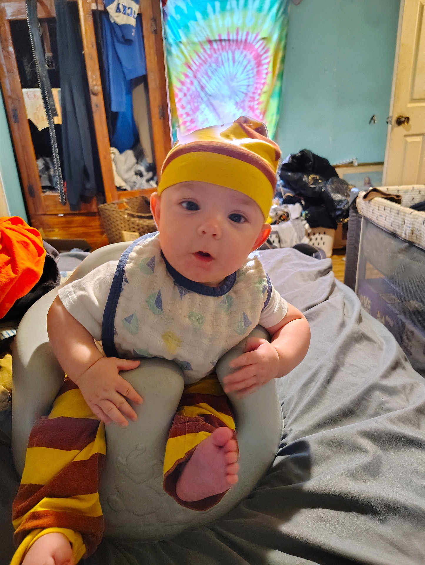 Jackson joined the competition — help win amazing prizes! baby, infant, child, indoor, seat, clothing, hat, pants, bib, foot, face, expression, furniture, bed, room, colorful, tie_dye, wooden_wardrobe, basket, blanket