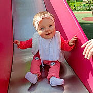 Amoryna a rejoint le concours — aidez-le/la à gagner de superbes lots ! baby_toddler_clothing, chute, fun, grass, hand, happy, human_body, leisure, magenta, outdoor_play_equipment, pink, play, playground, product, recreation, sitting, skin, sleeve, smile, toddler