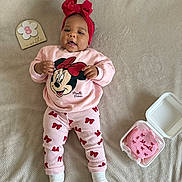 Ellyne a rejoint le concours — aidez-le/la à gagner de superbes lots ! baby, child, infant, pajamas, red_bow, headband, blanket, cake, milestone, 8_months, celebration, pink, smiling, lying_down, cute, clothing, person, indoor, portrait, happy