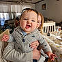 Derek is registered to the contest to win money with this photo: accessories, baby, bodypart, clothing, couch, cup, face, finger, furniture, glasses, hand, head, jewelry, knitwear, pants, person, photography, portrait, ring, sweater