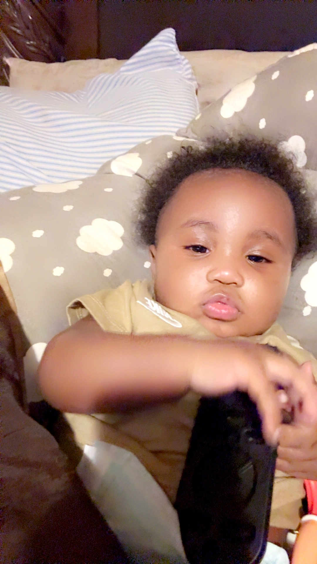 Kash is registered to the contest to win money with this photo: baby, child, face, pillow, cushion, bed, blanket, clothing, hand, indoor, person, infant, curly_hair, soft, resting, cute, young, toddler, closeup, skin