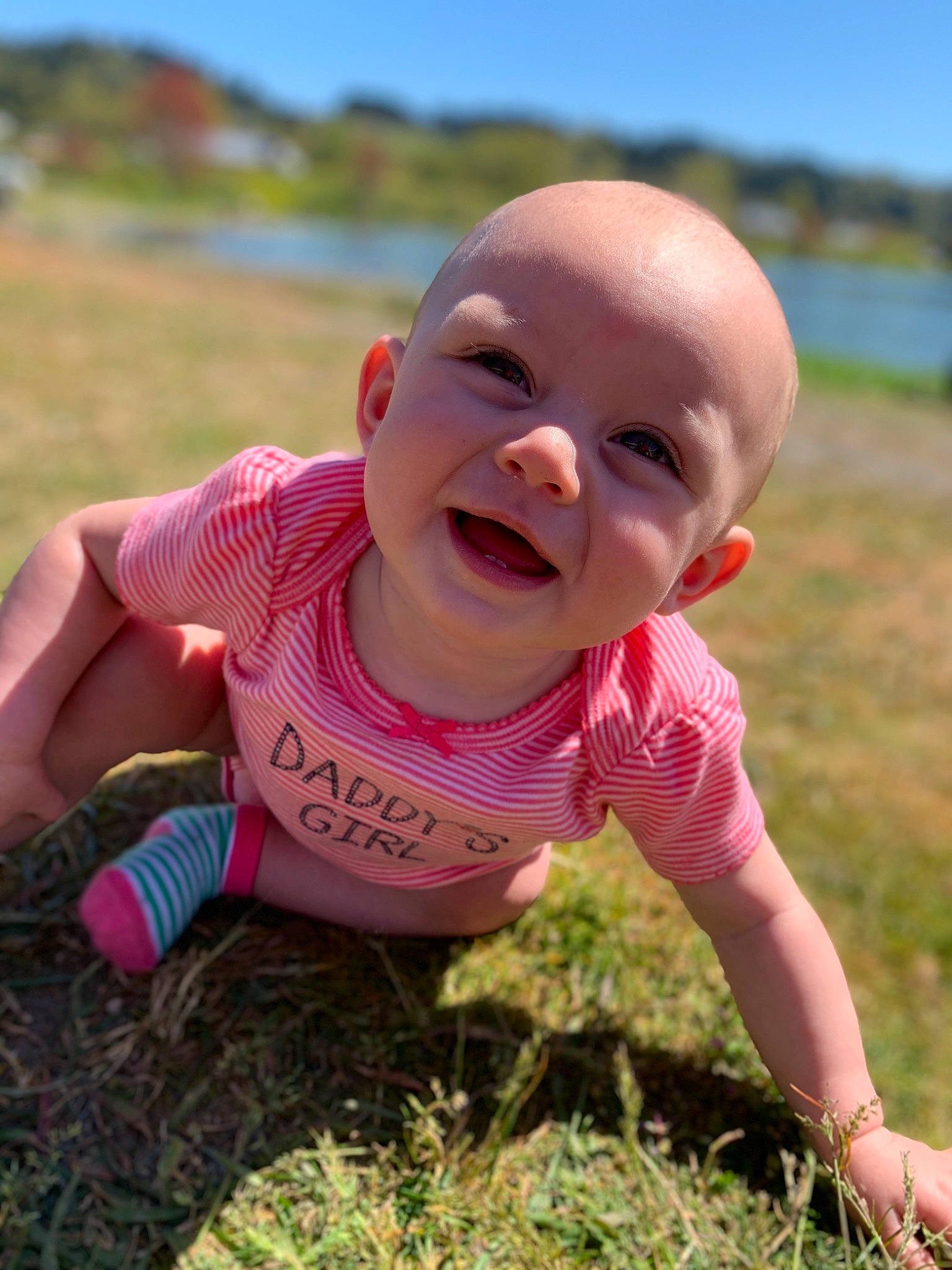 Alaina is registered to the contest to win money with this photo: baby, baby_laughing, baby_toddler_clothing, dress, finger, fun, grass, happy, iris, leisure, lip, mouth, people_in_nature, person, pink, plant, skin, sky, smile, standing