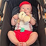 baby, infant, stroller, plush_toy, pacifier, red_cap, red_shorts, cute, child, indoor, car_seat, footwear_free, soft_toy, curious, relaxed, casual_clothing, light_skin, baby_girl_or_boy, childhood, comfort