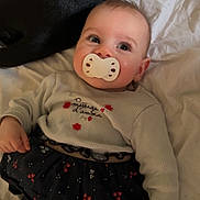 Yamie participe au concours pour gagner de l'argent avec cette photo : baby, pacifier, infant, bed, blanket, dog, black_dog, clothing, cute, child, lying_down, comfort, pet, animal, face, portrait, indoor, sleepwear, soft_lighting, rest