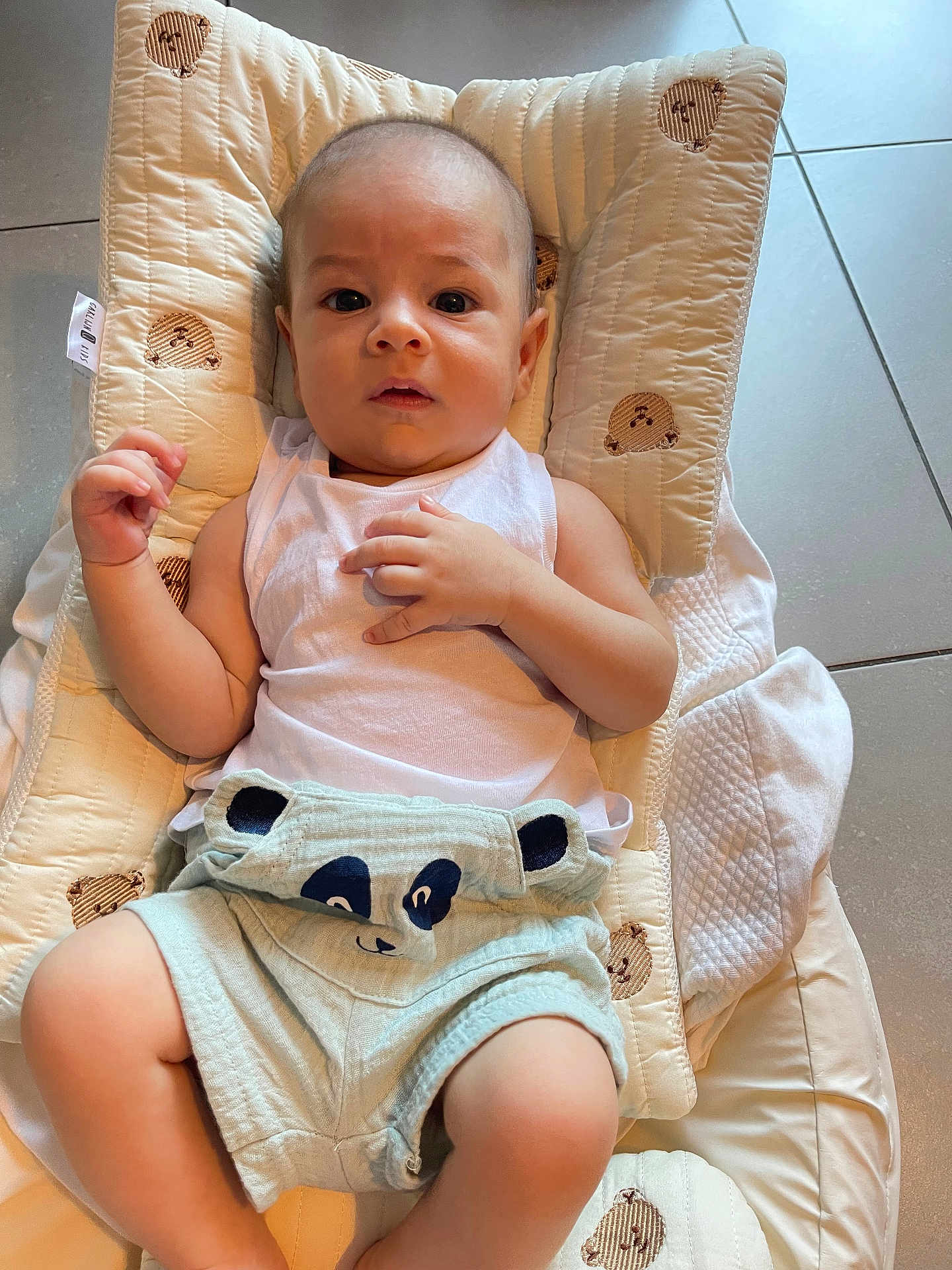 Gabriel a rejoint le concours — aidez-le/la à gagner de superbes lots ! baby, infant, child, cushion, bear_pattern, white_tank_top, panda_shorts, floor_tiles, looking_at_camera, indoor, light, cute, clothing, person, baby_clothes, face, hands, legs, expression, soft_toys_pattern