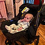 baby, car_seat, stroller, indoor, wooden_floor, pajamas, child, infant, face, hand, furniture, cozy, floor, seat, black, curious, sitting, toy, room, household