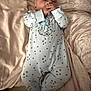 baby, onesie, pacifier, blanket, infant, sleepwear, child, soft_texture, cute, lying_down, bedroom, comfort, small_hands, face, footed_pajamas, star_pattern, resting, newborn, skin, indoors
