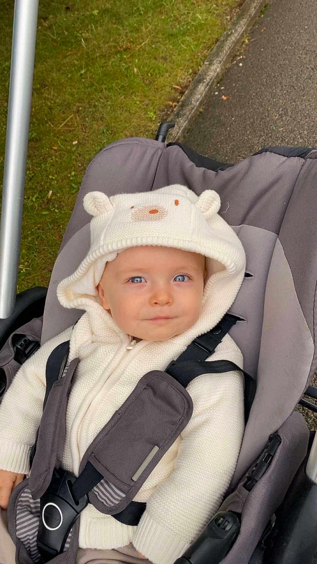 Emilio a rejoint le concours — aidez-le/la à gagner de superbes lots ! baby, child, stroller, hoodie, white_clothing, knitwear, blue_eyes, outdoor, grass, pavement, seatbelt, cute, infant, face, portrait, warm_clothing, baby_boy, baby_girl, person, sitting