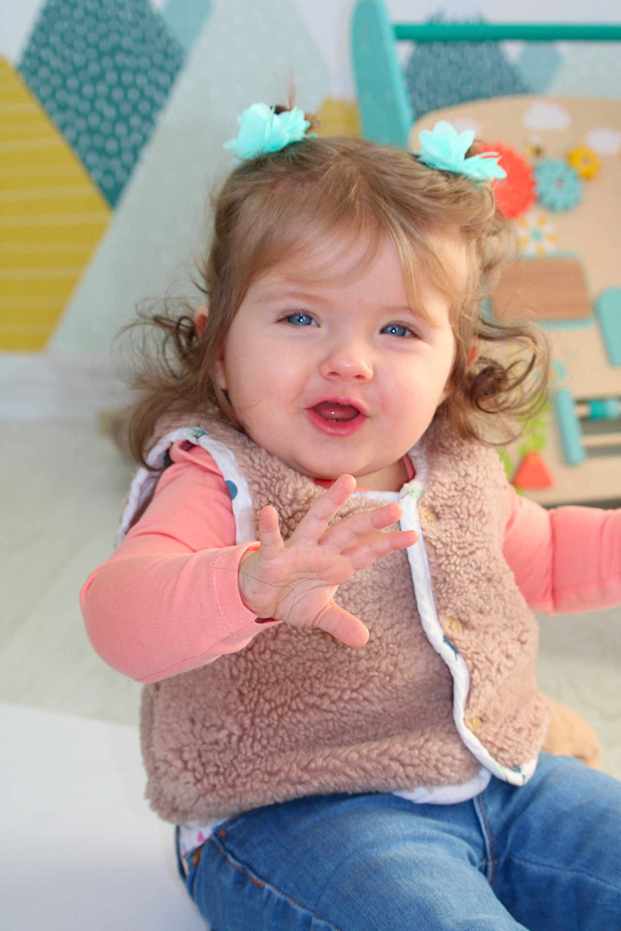 Sélène a rejoint le concours — aidez-le/la à gagner de superbes lots ! toddler, child, blue_eyes, smiling, vest, jeans, indoor, toy, playful, hair_ties, cute, happy, person, portrait, colorful_background, furniture, expression, candid, baby, clothing