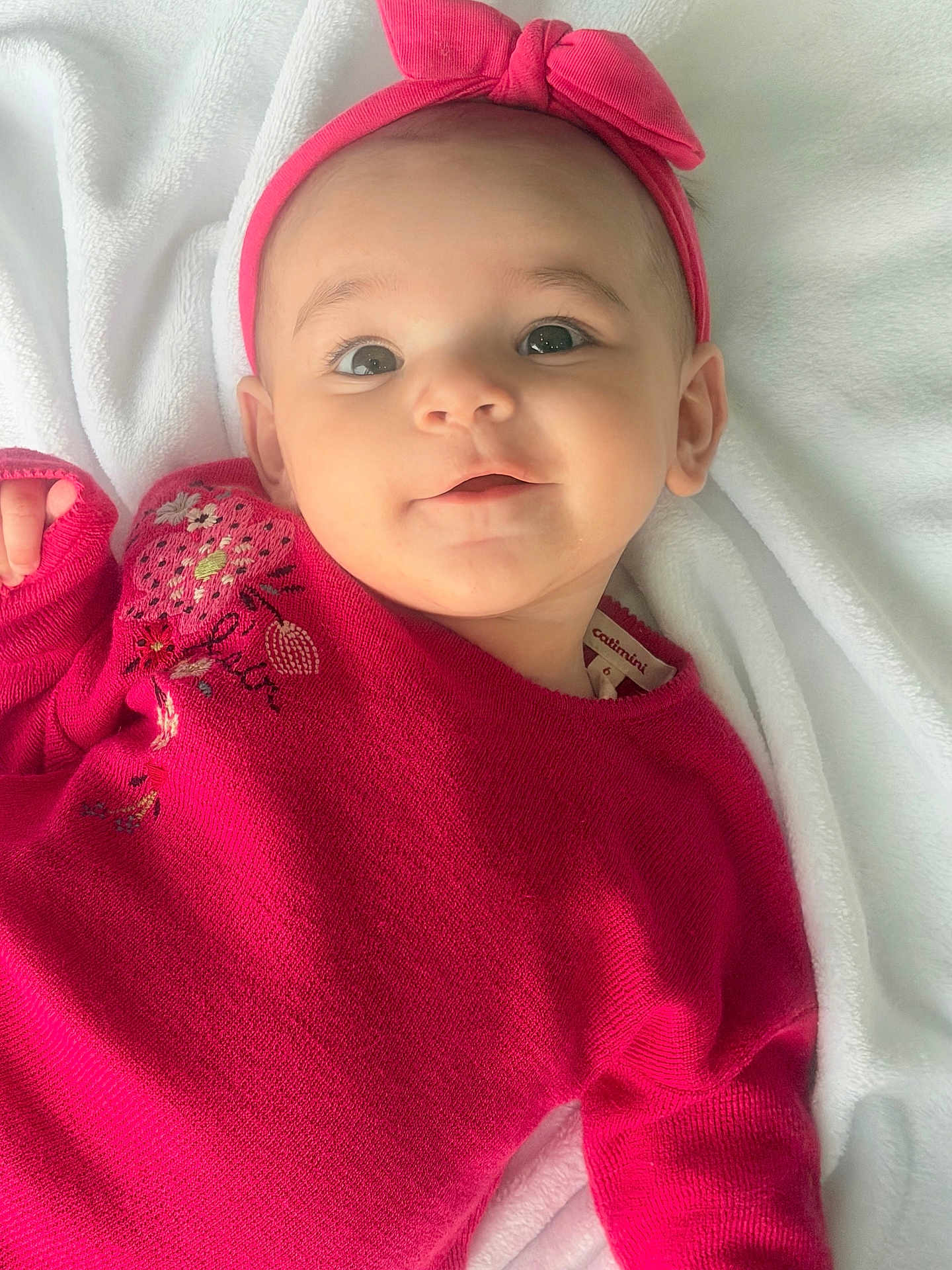 Lyna participe au concours pour gagner de l'argent avec cette photo : baby, infant, child, headband, pink_headband, sweater, red_sweater, blanket, lying_down, portrait, face, big_eyes, smile, cute, adorable, rosy_cheeks, soft_lighting, closeup, clothing, fabric