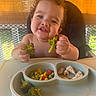 toddler, child, broccoli, food, high_chair, plate, vegetables, chicken, smiling, happy, curly_hair, indoor, meal, eating, baby, window, sunlight, bamboo_blinds, cute, portrait