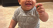 Albin is registered to the contest to win money with this photo: baby, child, toddler, smiling, sitting, indoor, kitchen, floor, leafy_greens, food, diaper, clothing, cabinet, appliance, curly_hair, cute, happy, person, young_child, casual