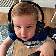 Jameson is registered to the contest to win money with this photo: blue_shirt, carpet, casual_clothing, chair, child, curious, cute, expression, floor, furniture, hand, headphones, home, indoor, looking_up, person, portrait, toddler, wooden_floor, young_child