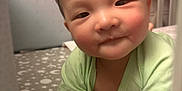 Haysen is registered to the contest to win money with this photo: baby, infant, crib, bedding, stars, moon, green_clothing, smile, face, hands, indoor, closeup, person, cute, child, bed, sleeping_area, soft_lighting, young, resting