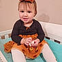 toddler, child, baby, orange_bow, pumpkin_skirt, white_tights, crib, pacifier, smiling, indoor, portrait, cute, festive, orange, black_shirt, happy, sitting, headband, clothing, toy